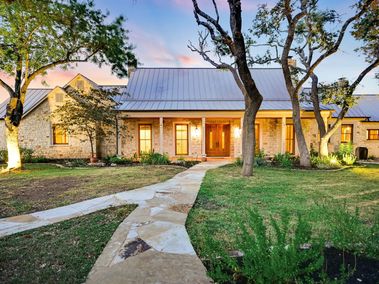 Exterior of large, stone home with walkway in Driftwood, Texas