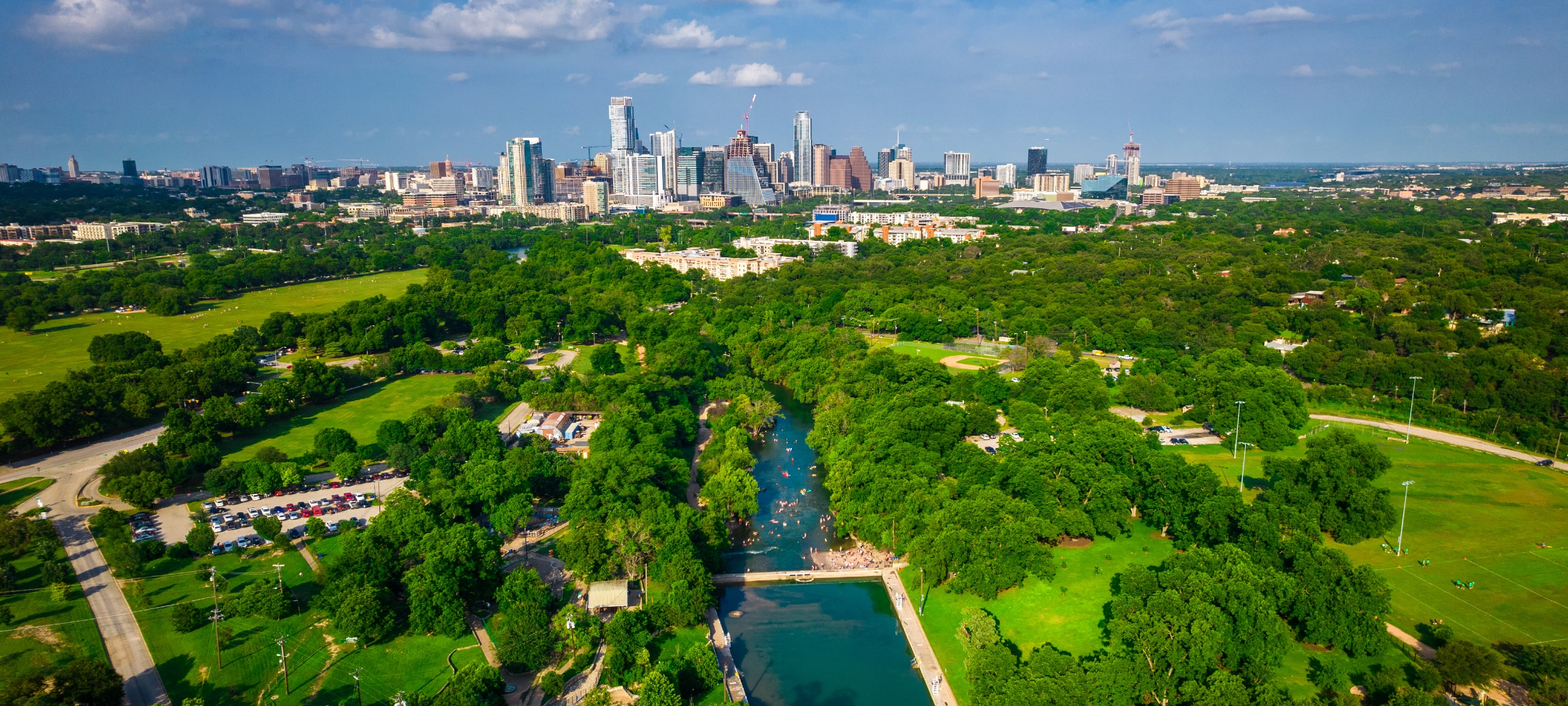 Aerial view over Barton Springs and Barton Creek with Austin skyline in distance